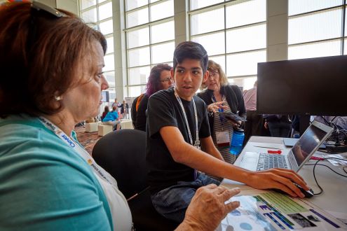 A student helps a teacher at the ISTE Conference & Expo.