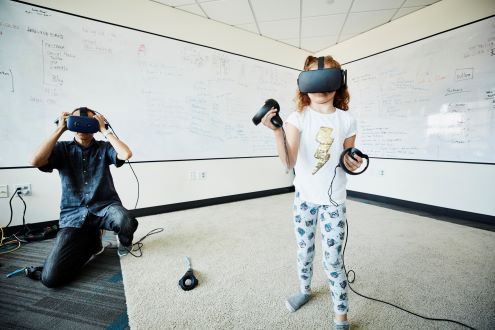 A child wearing an augmented reality headset while an adult looks on