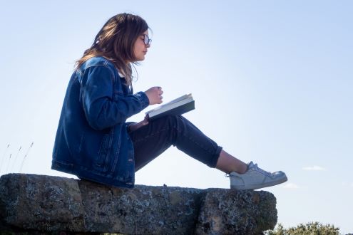 A student reads a book outside to take a break from her digital device.