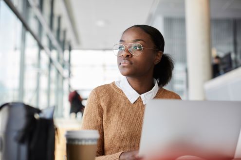 A student at a laptop stares out the window