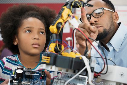 A student works on a robotics project with her teacher