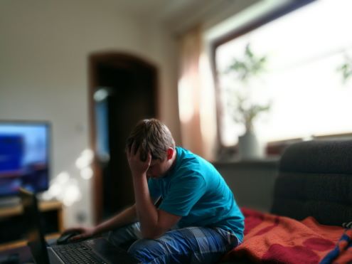 Un niño en la computadora con colgar en la cabeza en la frustración