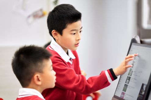 Two boys in china work on a computer