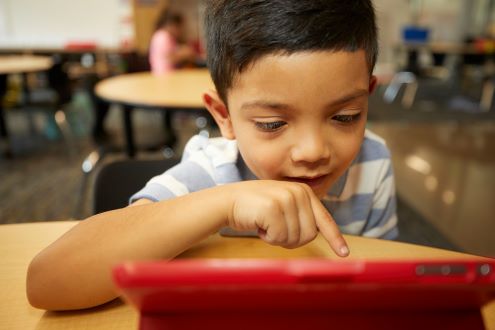 a young boy uses a tablet in school