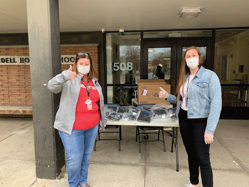 Two teachers hand out laptops during COVID-19