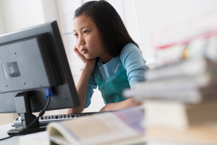 a girl looks at a computer screen