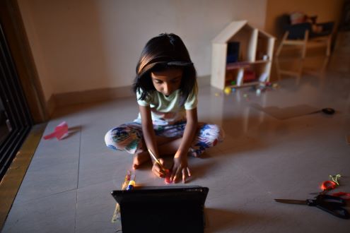 A girl works on a craft during an online lesson