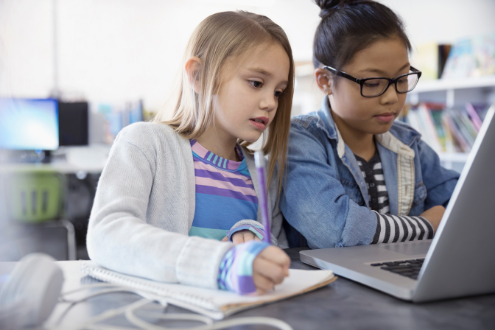 Two elementary school girls coding with a laptop