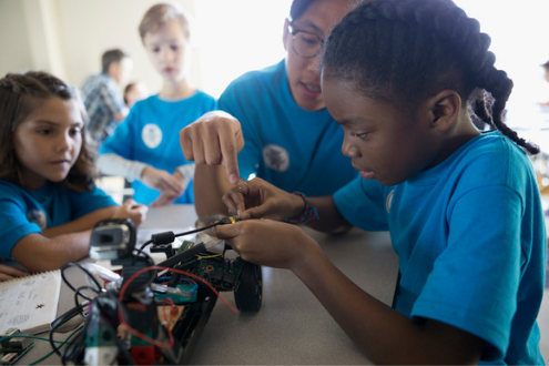Three children build a robotic car together