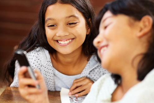 two girls laughing at something on a phone