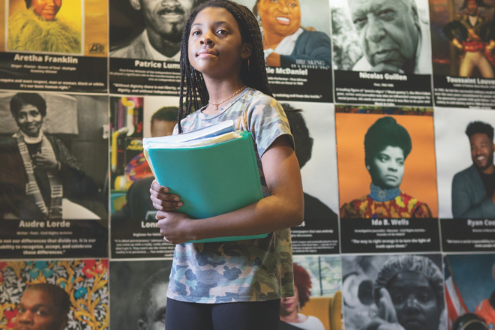 a girl stands in front of a wall celebrating Black leaders