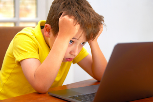 A boy looks frustrated while working online