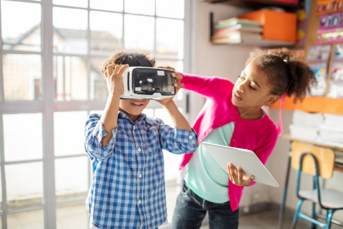 A girl helps a boy with a VR headset
