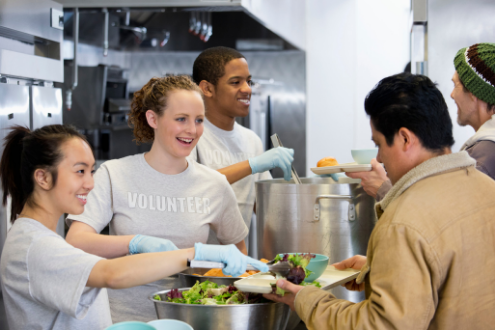three teenagers serve a meal in a shelter