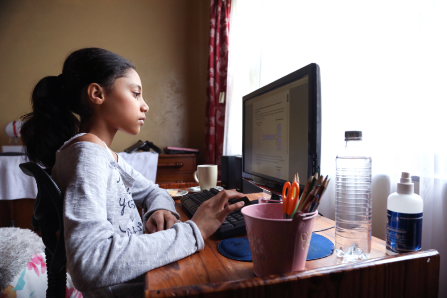 una niña aprende en línea en casa