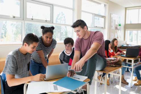 a group of students surround a laptop