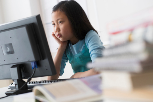 a child searches the internet on a desktop computer