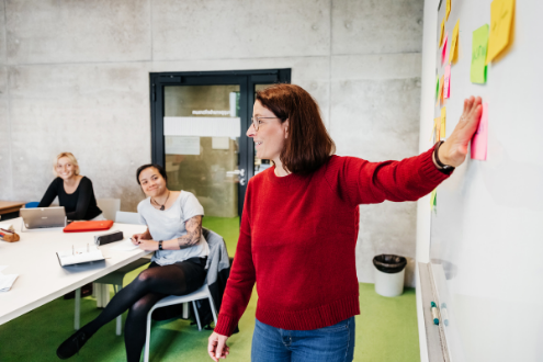 A teacher stands in front of a whiteboard