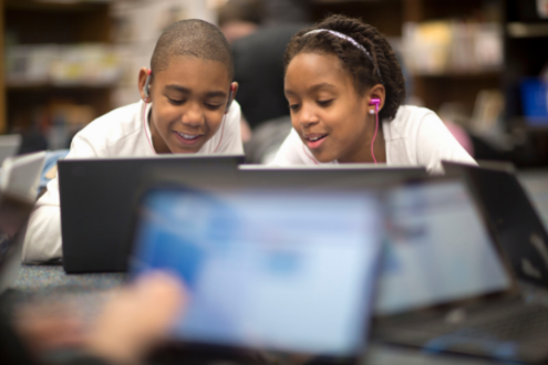 Two students huddled in front of a laptop