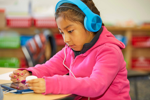 Una niña escucha un libro en su tableta.