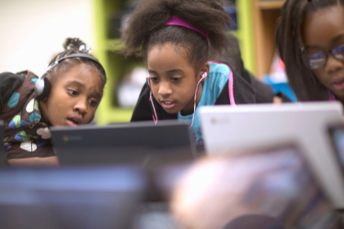 Three girls work together at a laptop