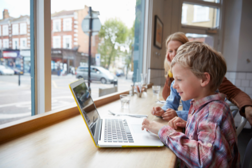 A boy uses a laptop in a cafe to do school work