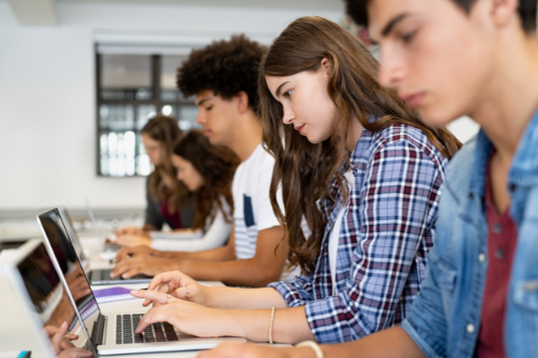 A row of students using laptops at school