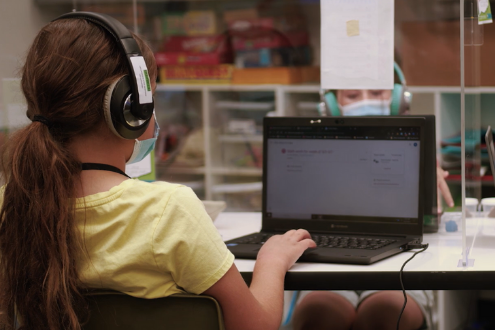 niña sentada frente a una computadora portátil en la escuela