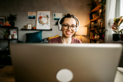 A teacher smiles behind a laptop while presenting a webinar