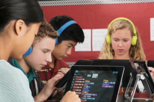 Un grupo de estudiantes trabajan juntos en computadoras portátiles programando chatbots