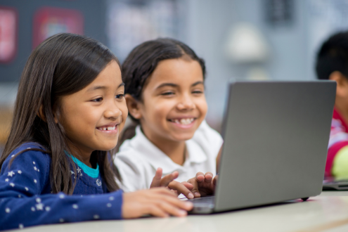 Two girls work on video project using a laptop.