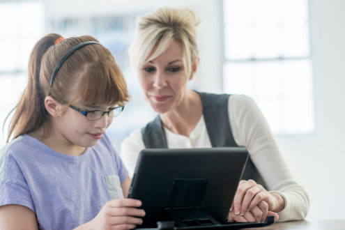 A teacher helps a visually impaired student navigate digital content.