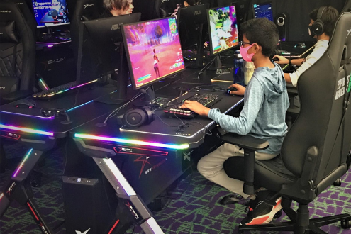 Teenage boy at an esports club plays a game on a large screen.