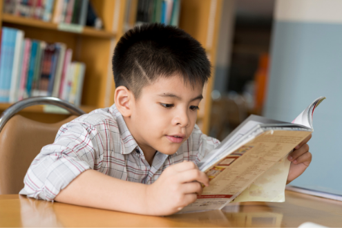 a boy sitting in a library reading a book