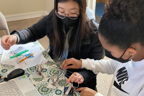 Two students wearing masks work with electric circuitry in school
