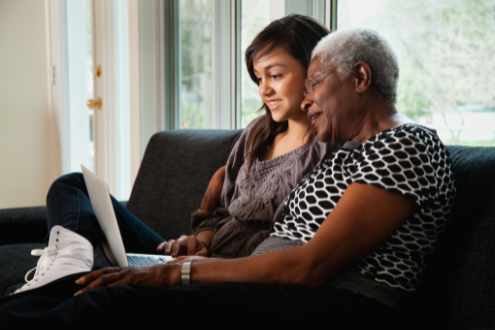 A teenager showing an elderly woman how to use a computer