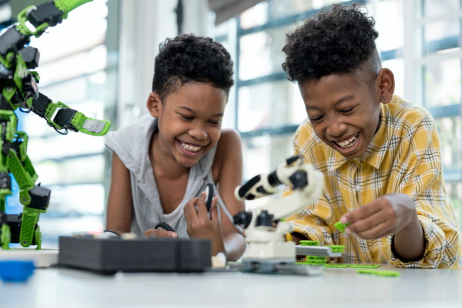 Two smiling students work on a robotics project in school