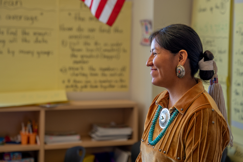 Un nativo americano con vestimenta tradicional habla con una clase de estudiantes.