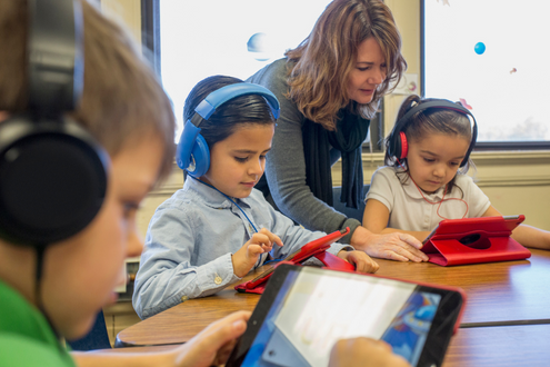 a kindergarten teacher helps her students use their iPads.