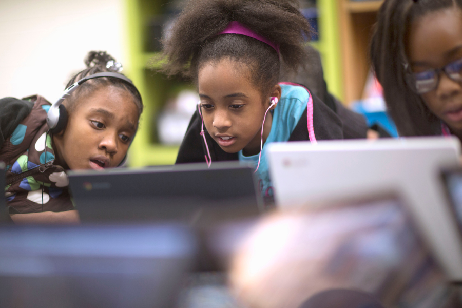 Dos niñas detrás de una computadora portátil de la escuela programan juntas un chatbot