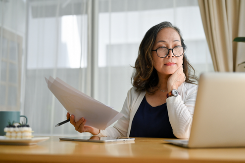 a teacher looks at a computer screen while grading papers