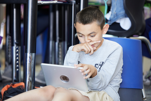 a boy stares at a school laptop looking perplexed