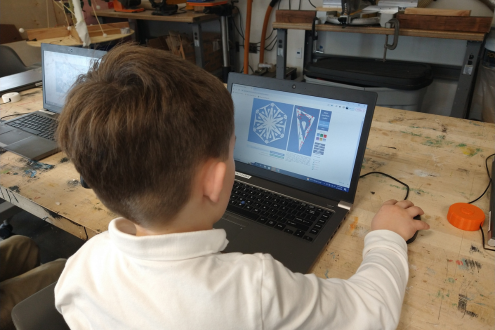 Mirando a un niño desde atrás sentado frente a una computadora portátil diseñando un copo de nieve digital