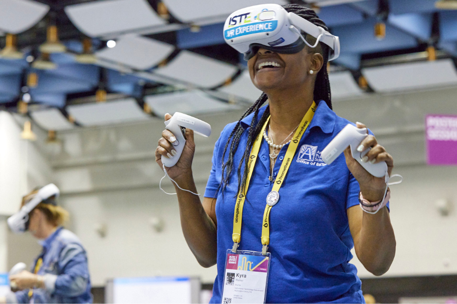 A woman wearing a VR headset smiles in the VR Playground at ISTELive 22