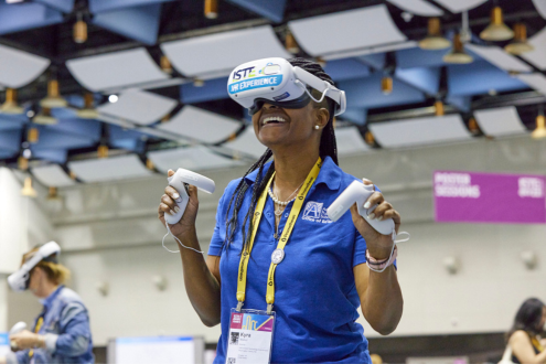 A woman wearing a VR headset smiles in the VR Playground at ISTELive 22
