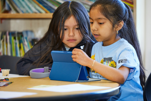 Dos niñas en un salón de clases mirando un ipad