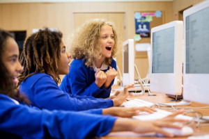 Tres chicas animan mientras juegan un juego en una computadora