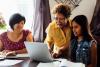 A student is doing her homework while a grandmother and mother help