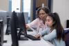 A teacher and a student working at a desktop computer