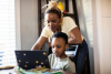 A mom and her son look at a website together on a laptop